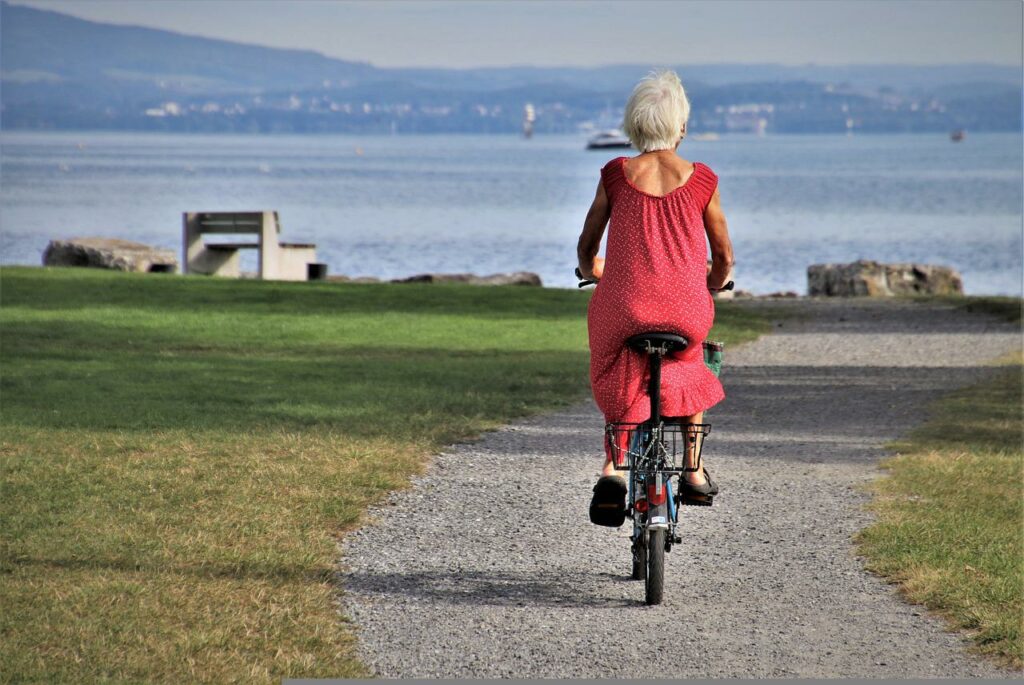 Seniorin fährt Fahrrad am See Fit im Alter So geht es