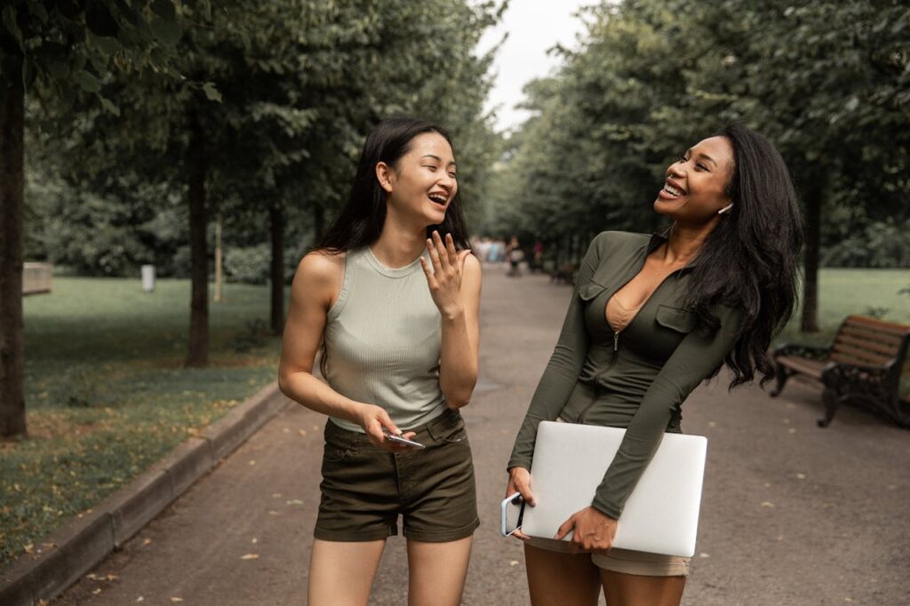 Frauen Spaziergang Park Laptop zugeklappt kulturelle Diversität Asiatin Afroamerikanerin Digital Detox Warum digitale Auszeiten so wichtig sind